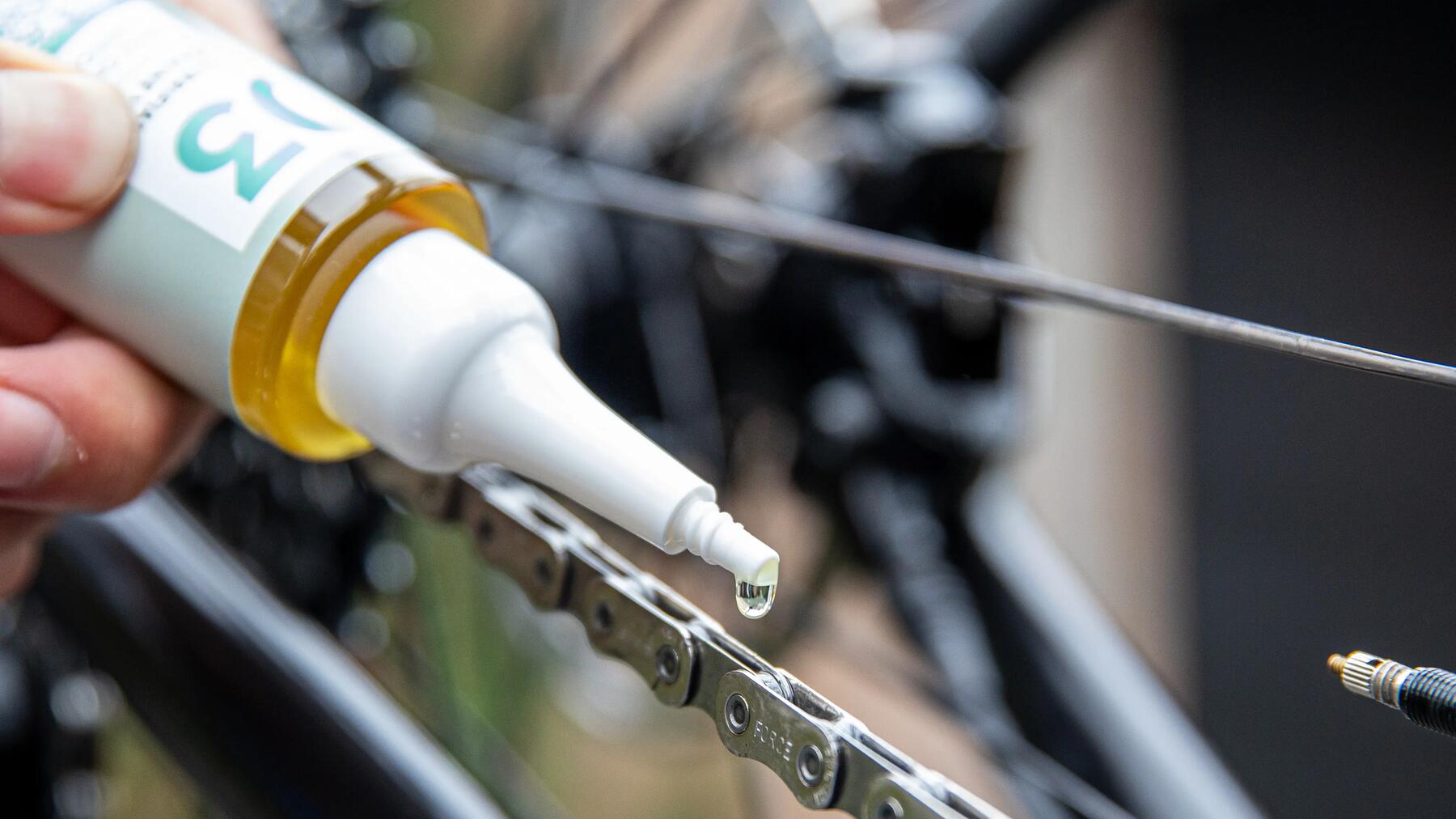 Een fietsketting word gesmeerd met smeermiddel van Decathlon