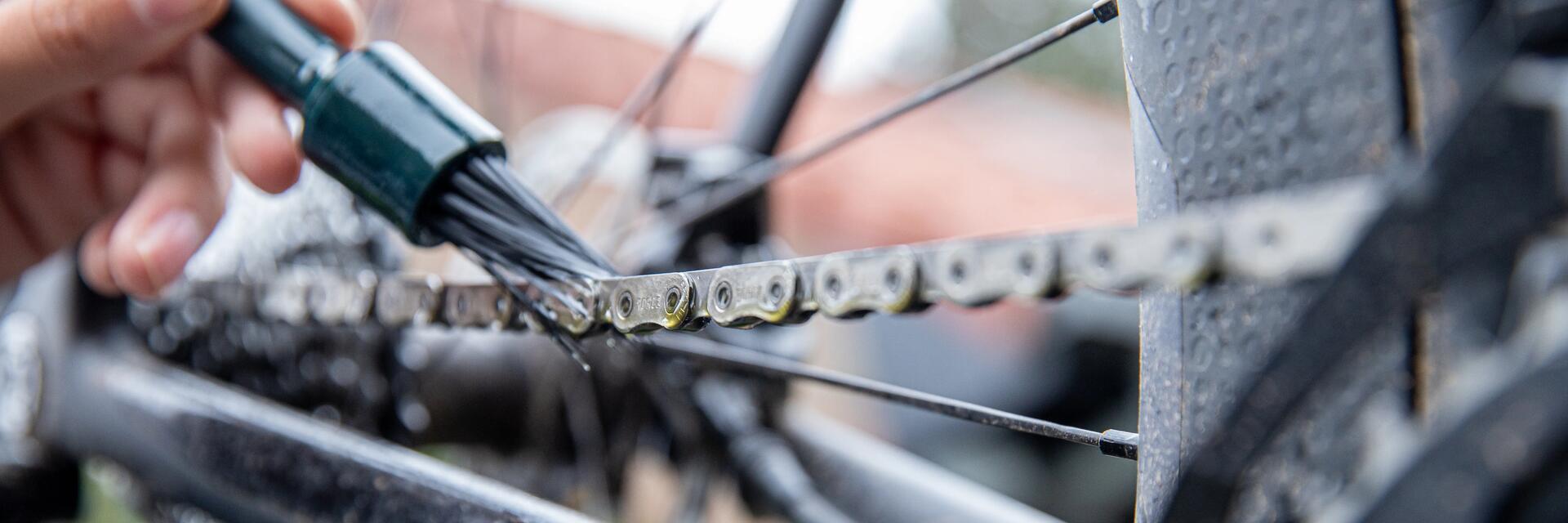 iemand doet onderhoud aan de ketting van zijn fiets