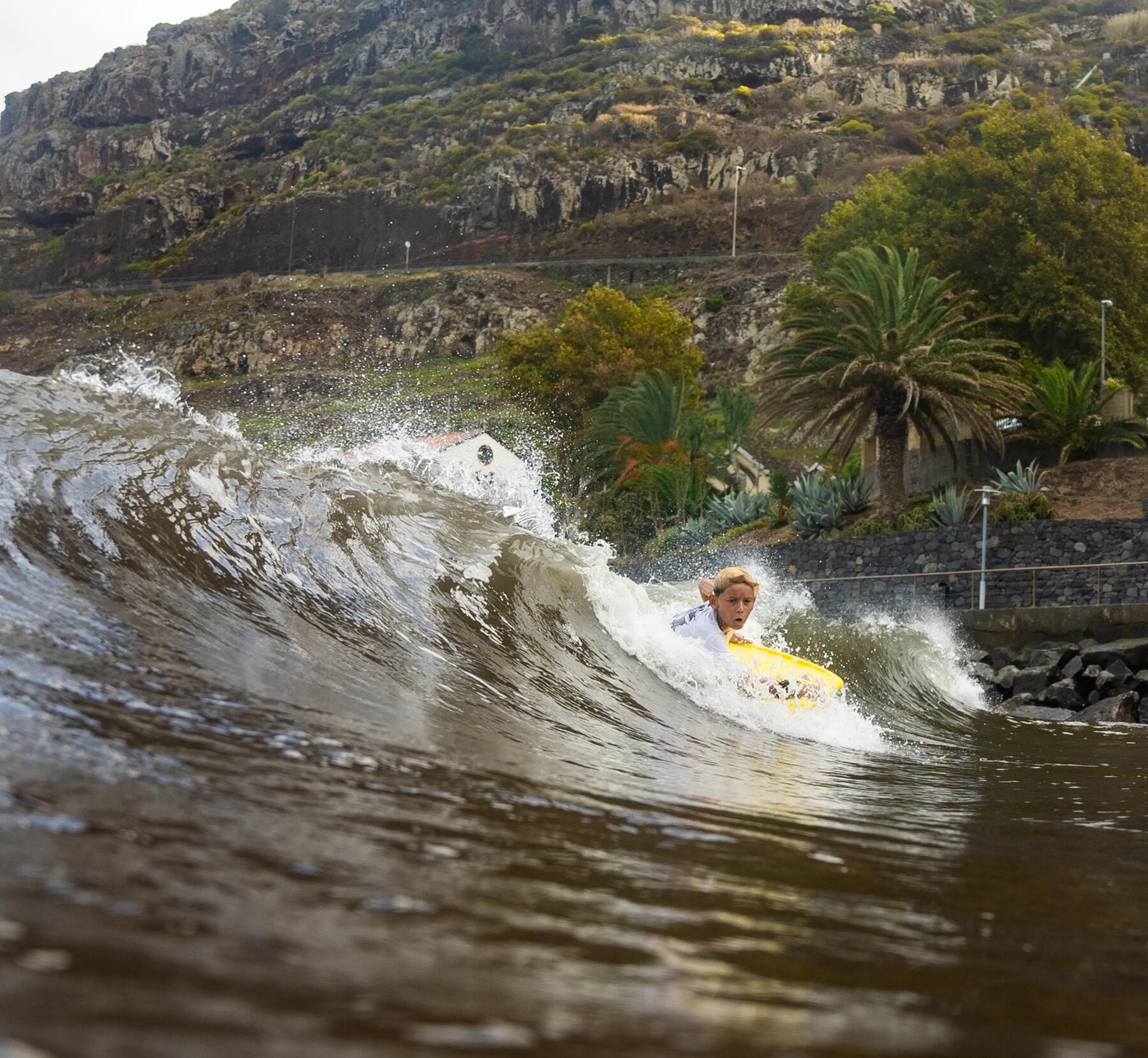 Ein Kind surft eine Welle mit einem Bodyboard