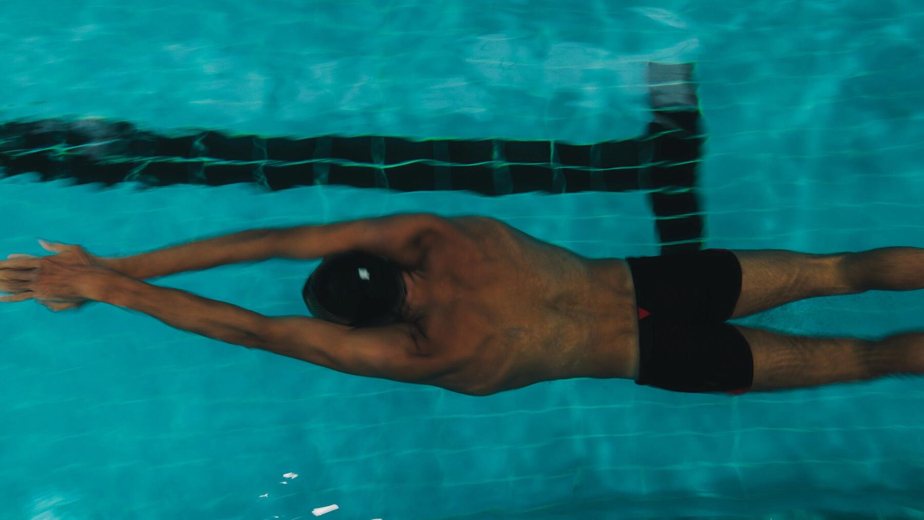 Mann macht Brustschwimmen mit Badekappe