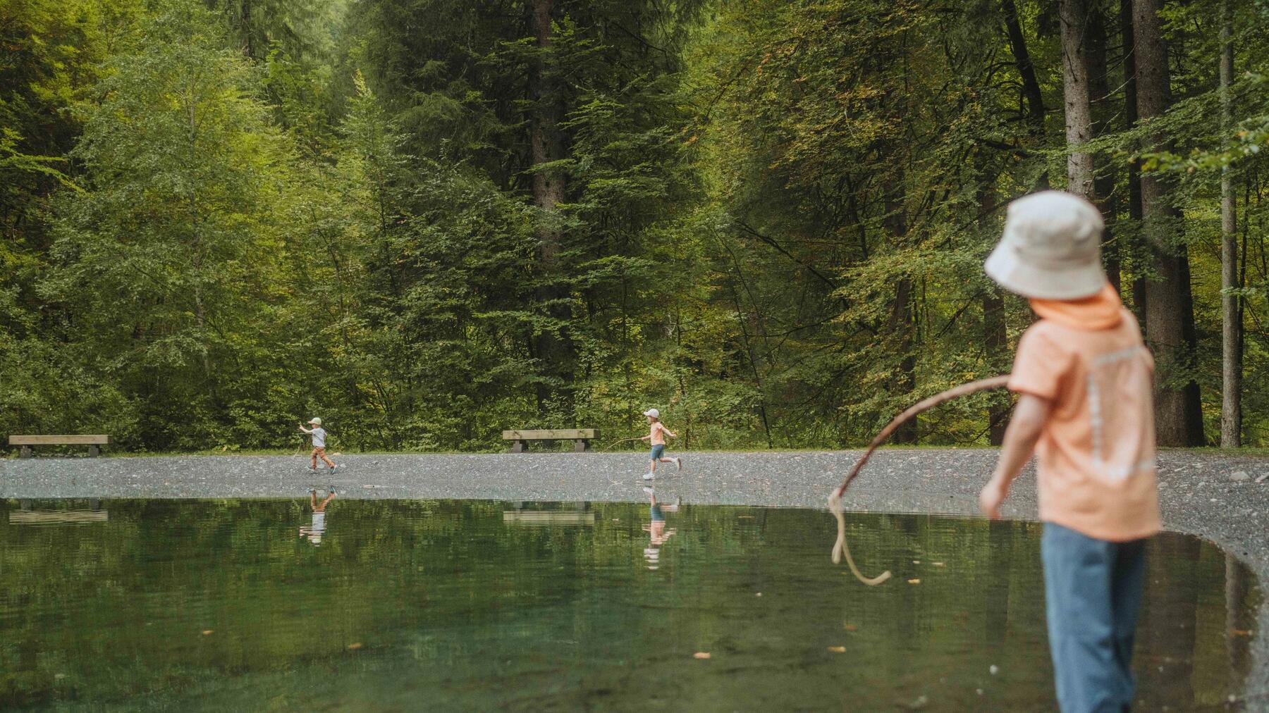 Kind steht in Wanderschuhen am See