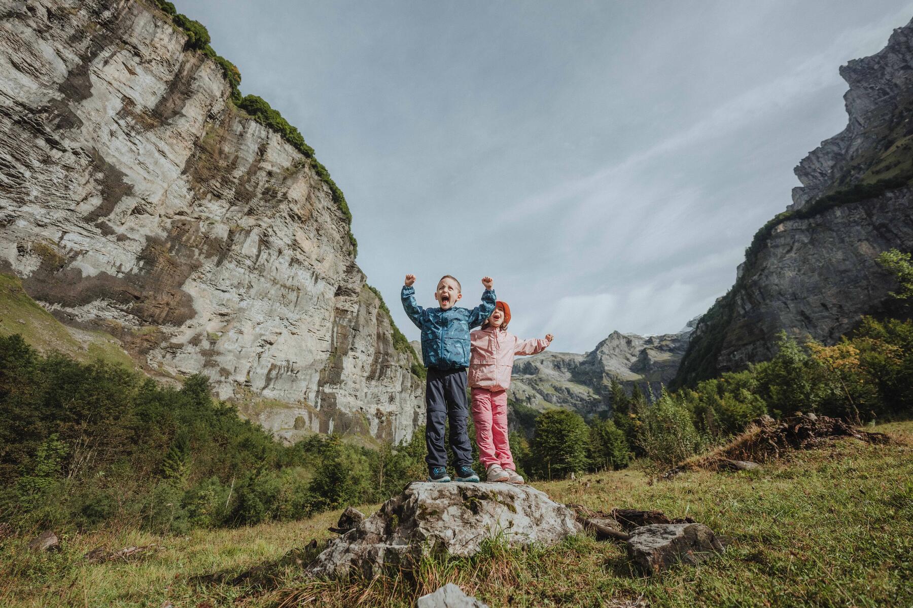 Zwei Kinder stehen auf einem Stein in guten Wanderschuhen