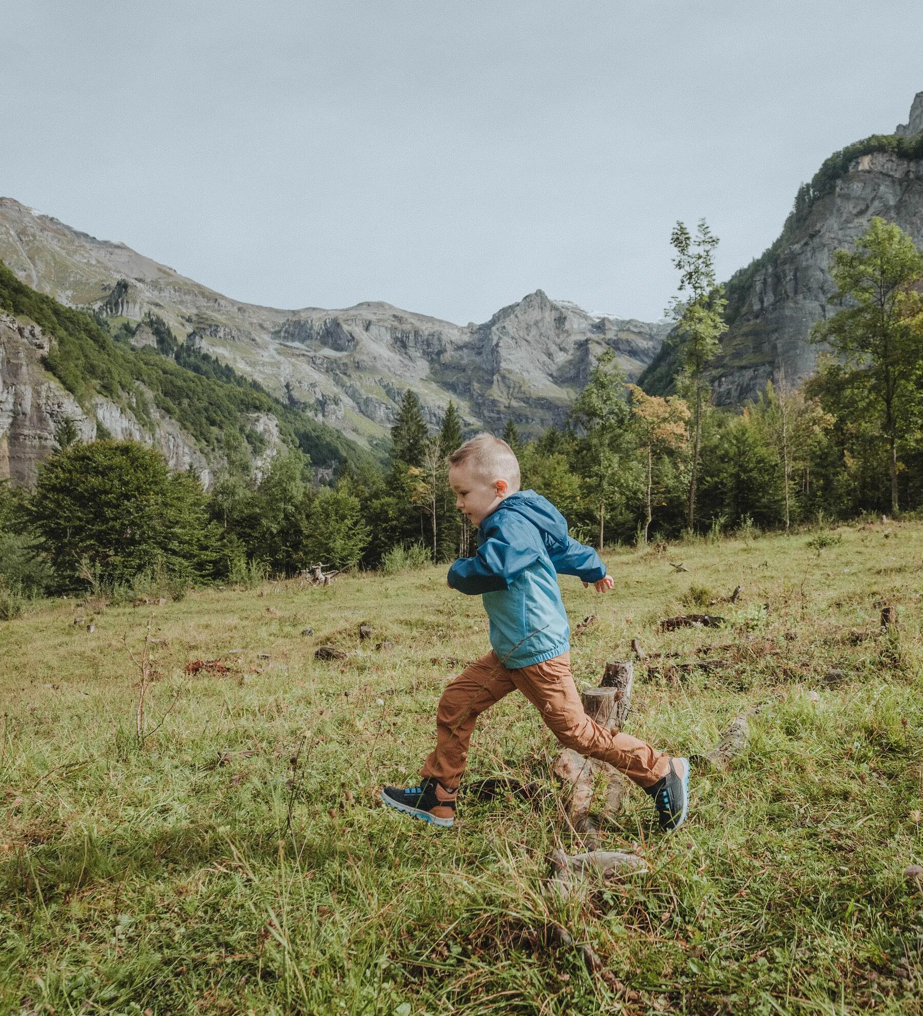 Kind läuft in Wanderschuhen über eine Wiese