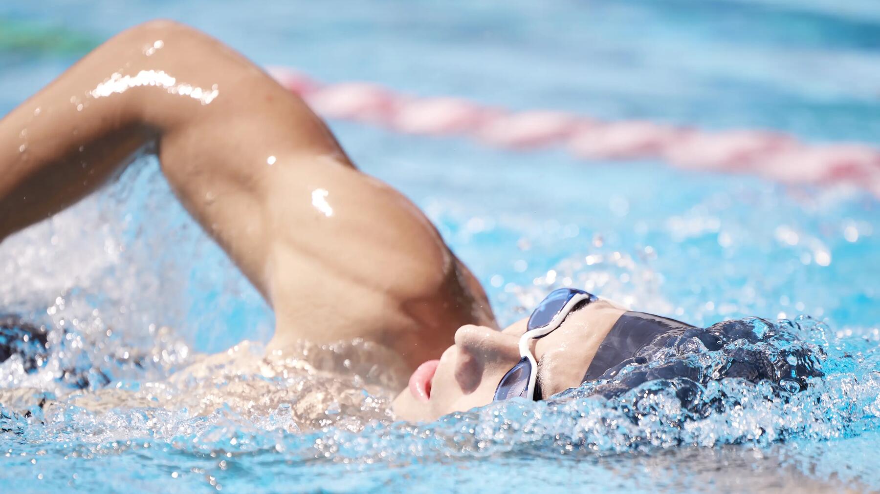 Osoba w czepku i w okularach pływająca w basenie