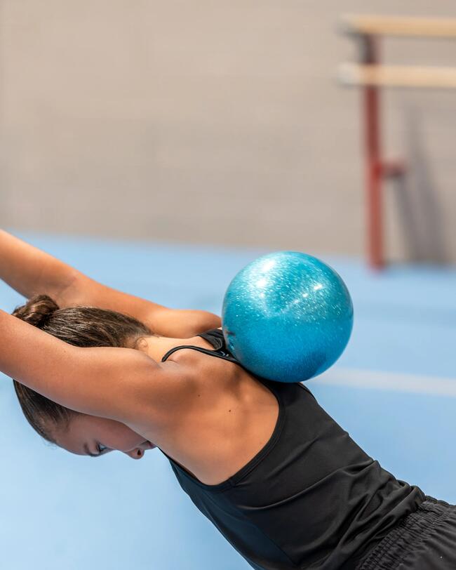 Ein Mädchen rollt einen Gymnastikball über ihren Rücken.