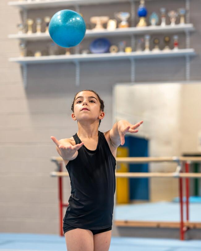 Mädchen wirft kleinen Gymnastikball nach oben.