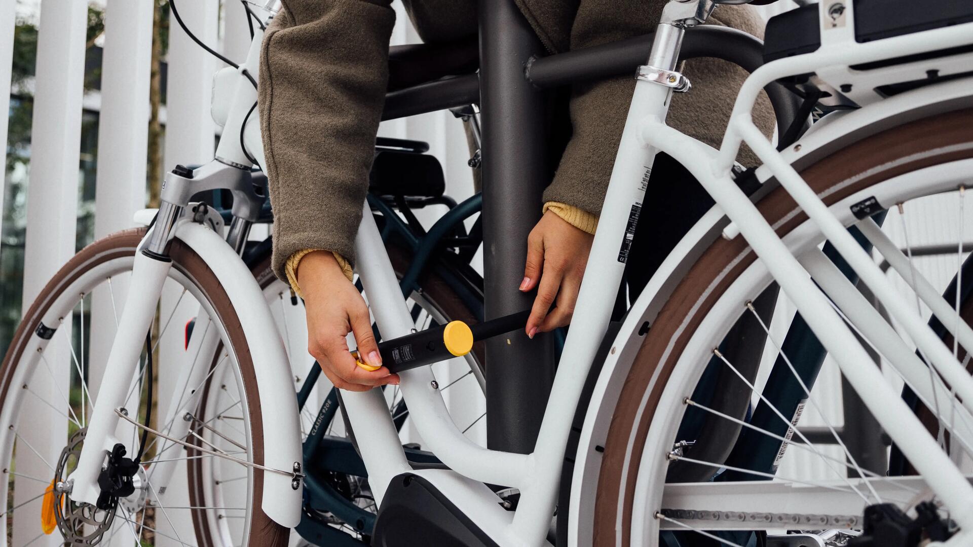 Iemand die een fiets vastmaakt met een U-slot