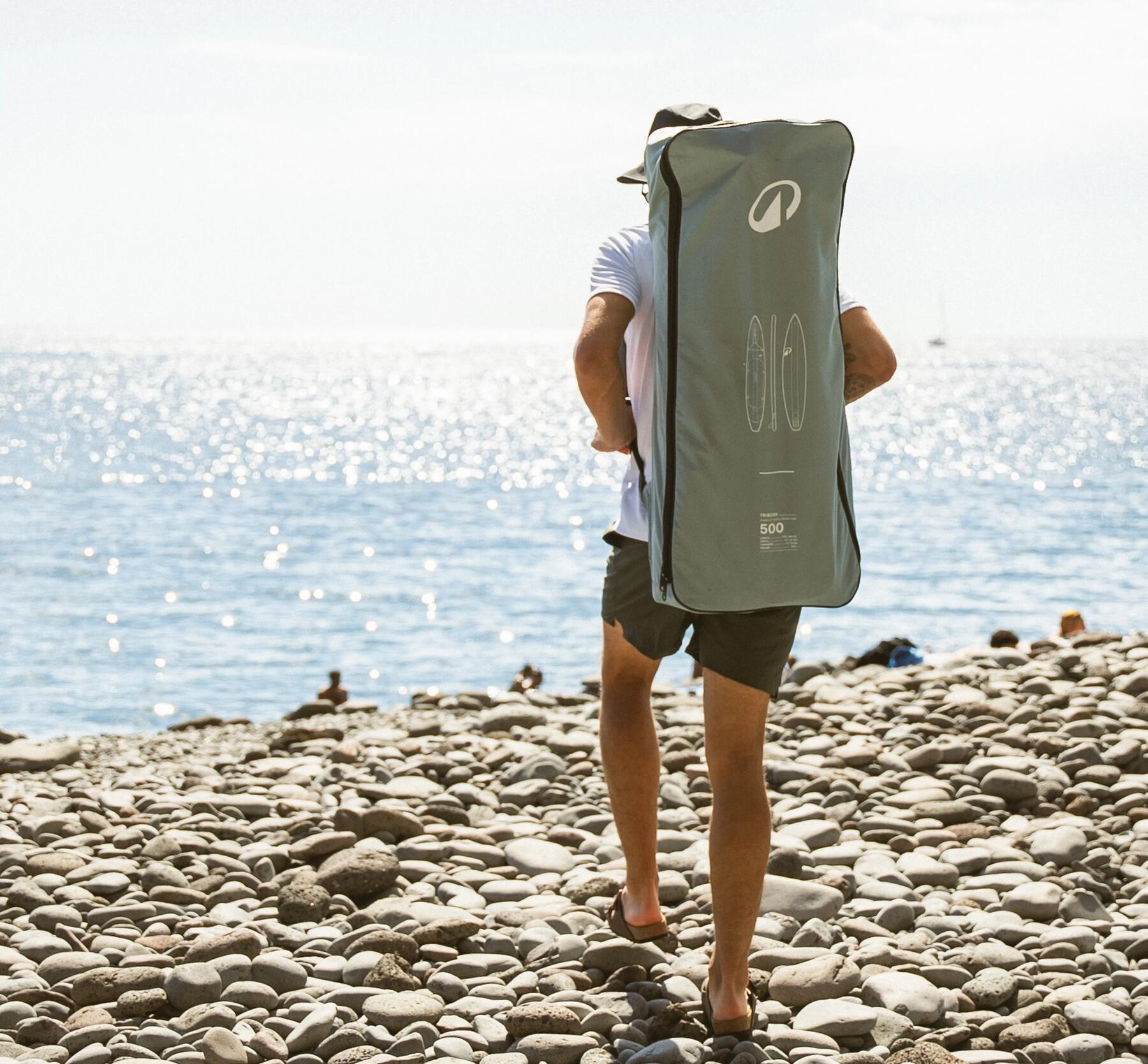 Ein Mann geht mit SUP & Pumpe an den Strand