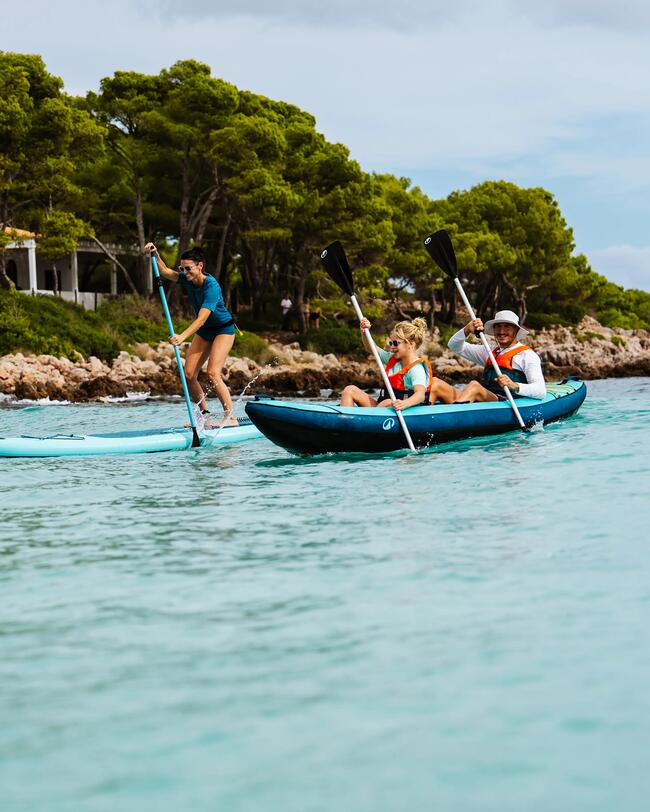 Drei Personen genießen Wassersport mit Kajak und Paddleboard auf türkisfarbenem Wasser, umgeben von grünen Bäumen.