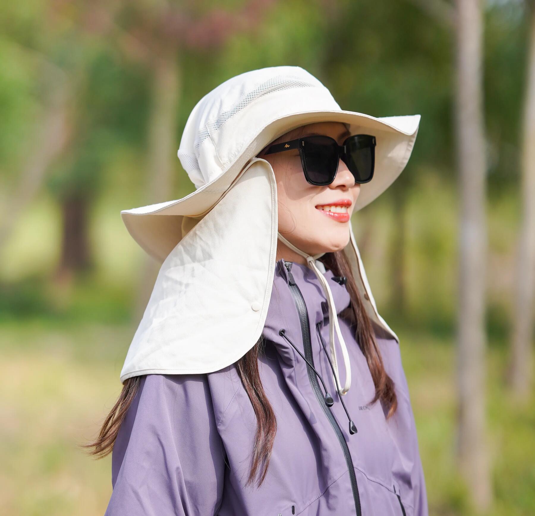 Frau steht mit Hut, Brille und Brillenband in der Sonne