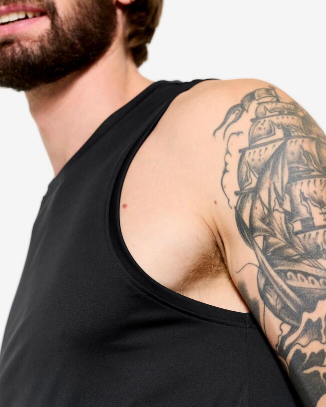 Nahaufnahme der Schulter und Achselhöhle eines Mannes mit tätowiertem Arm in einem schwarzen Tanktop.