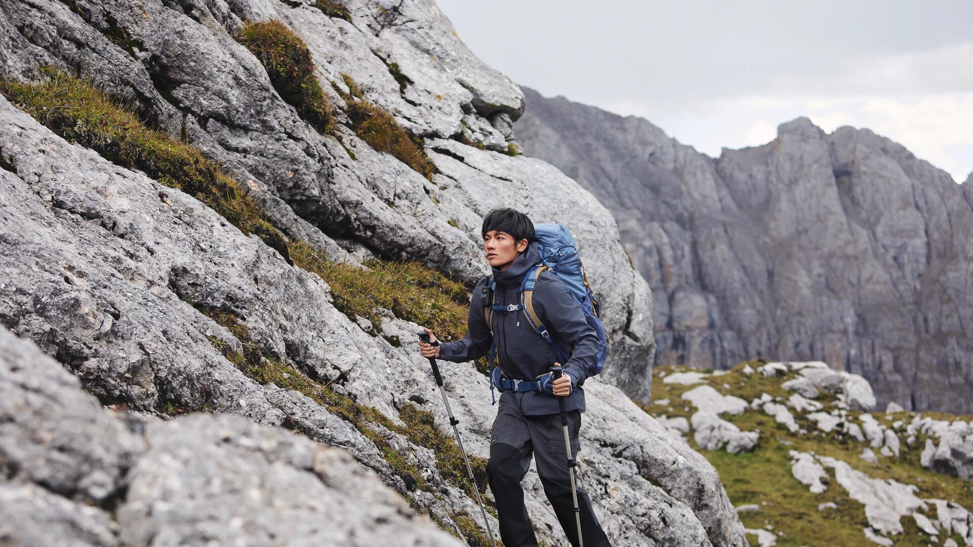 mężczyzna w odzieży trekkingowej wędrujący po górach zimą z kijami trekkingowymi
