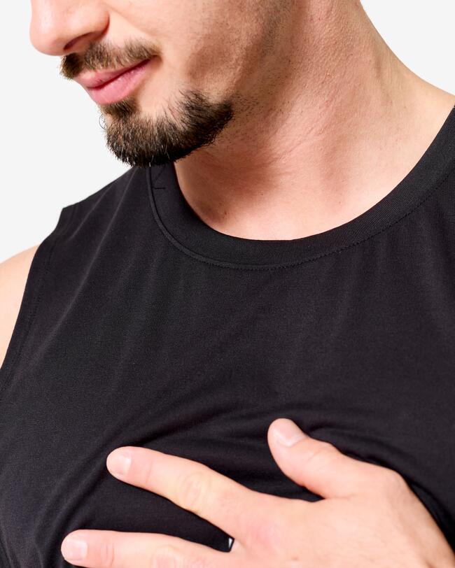 Nahaufnahme des Oberkörpers eines Mannes mit Bart in schwarzem Tanktop und Hand auf der Brust.