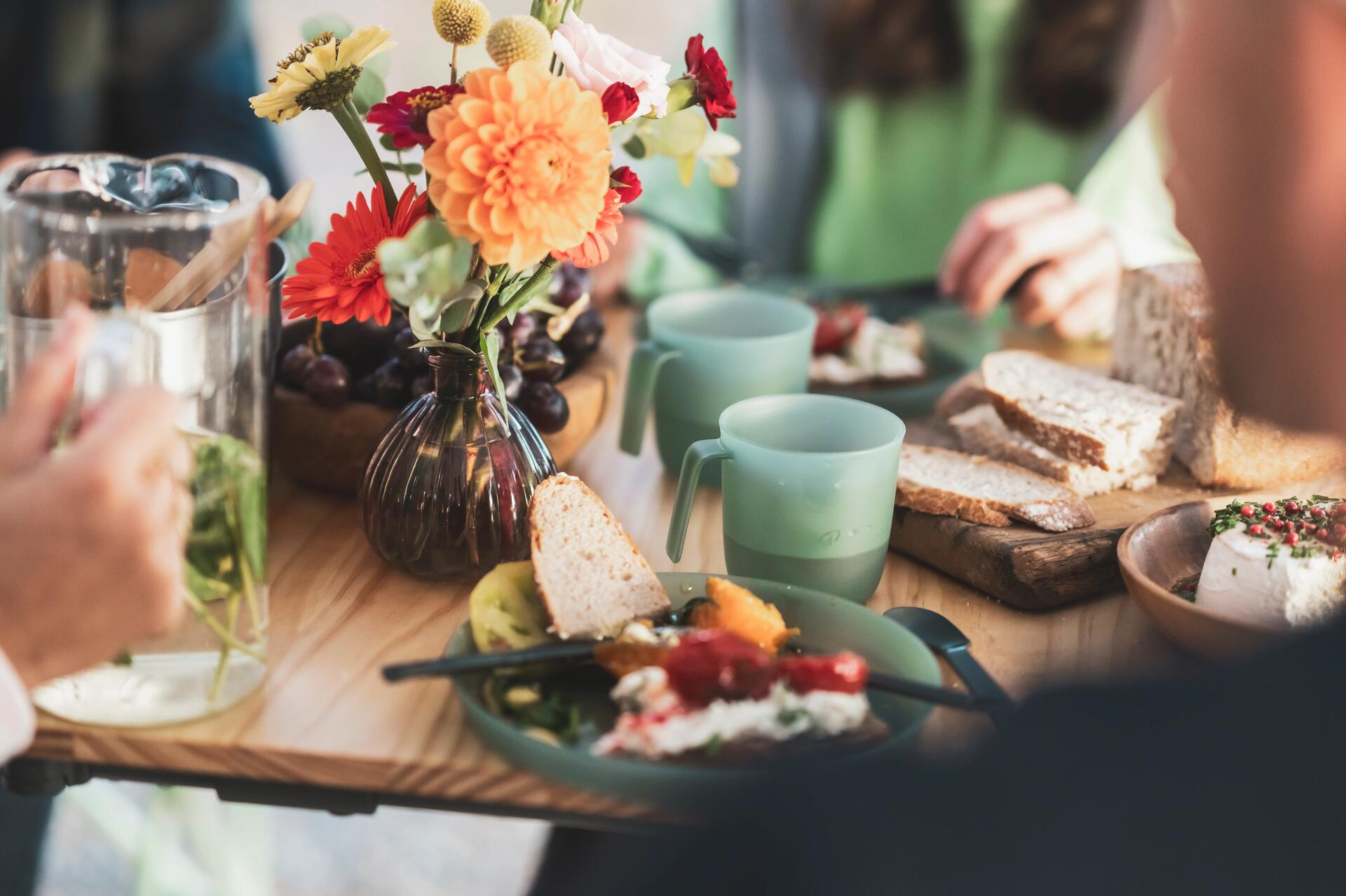 Tafel met broodjes,  drinken en theekoppen en decoratie (bloemetjes). 