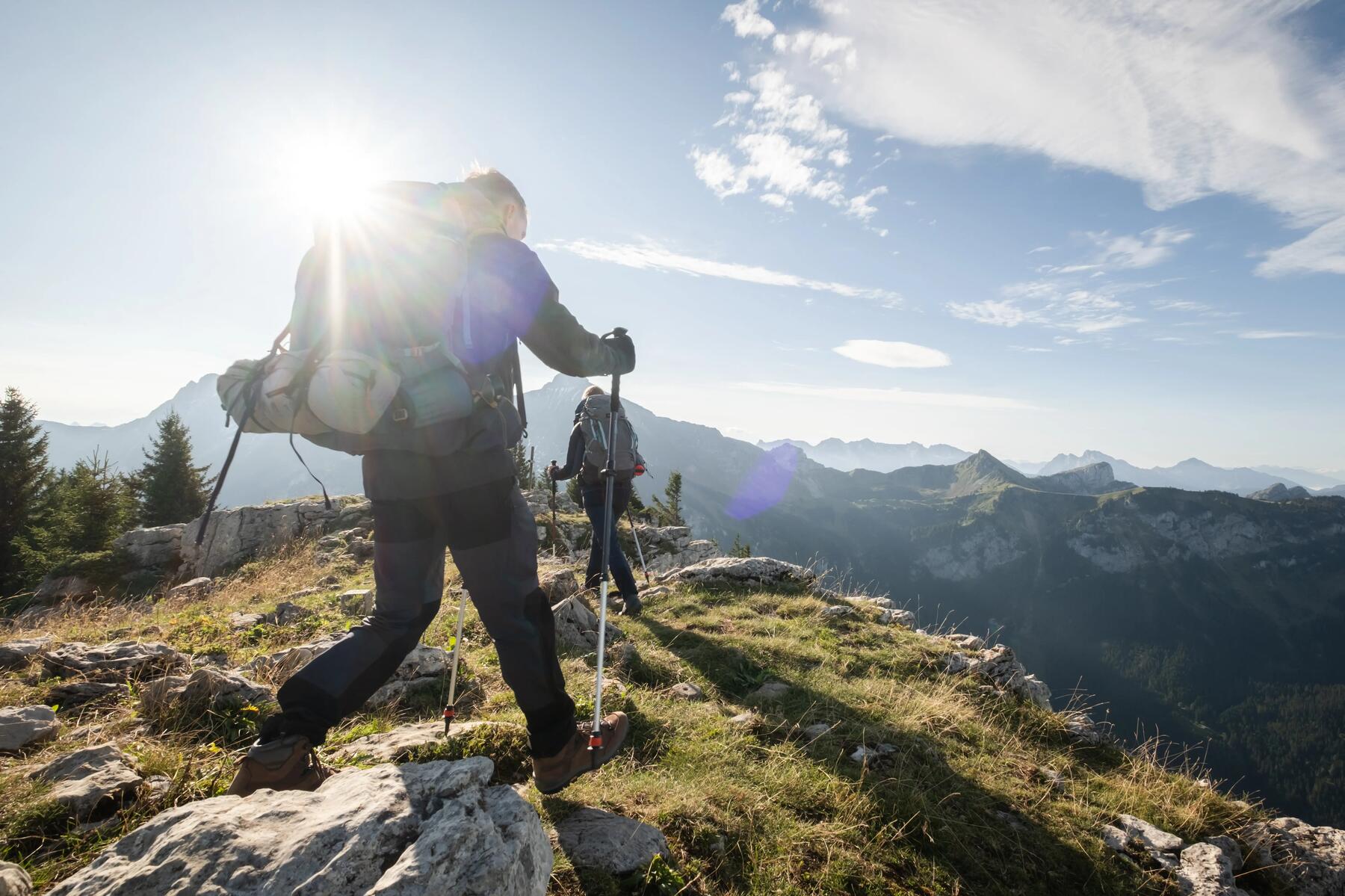 Ludzie z plecakami i z kijkami trekkingowymi wędrujący po górach