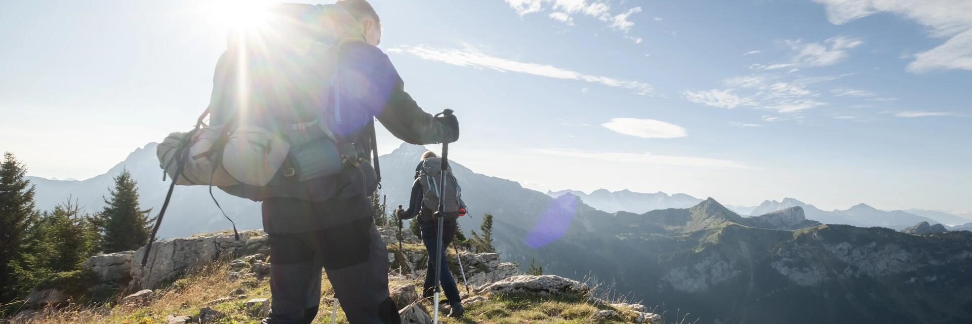 Ludzie z plecakami i z kijkami trekkingowymi wędrujący po górach