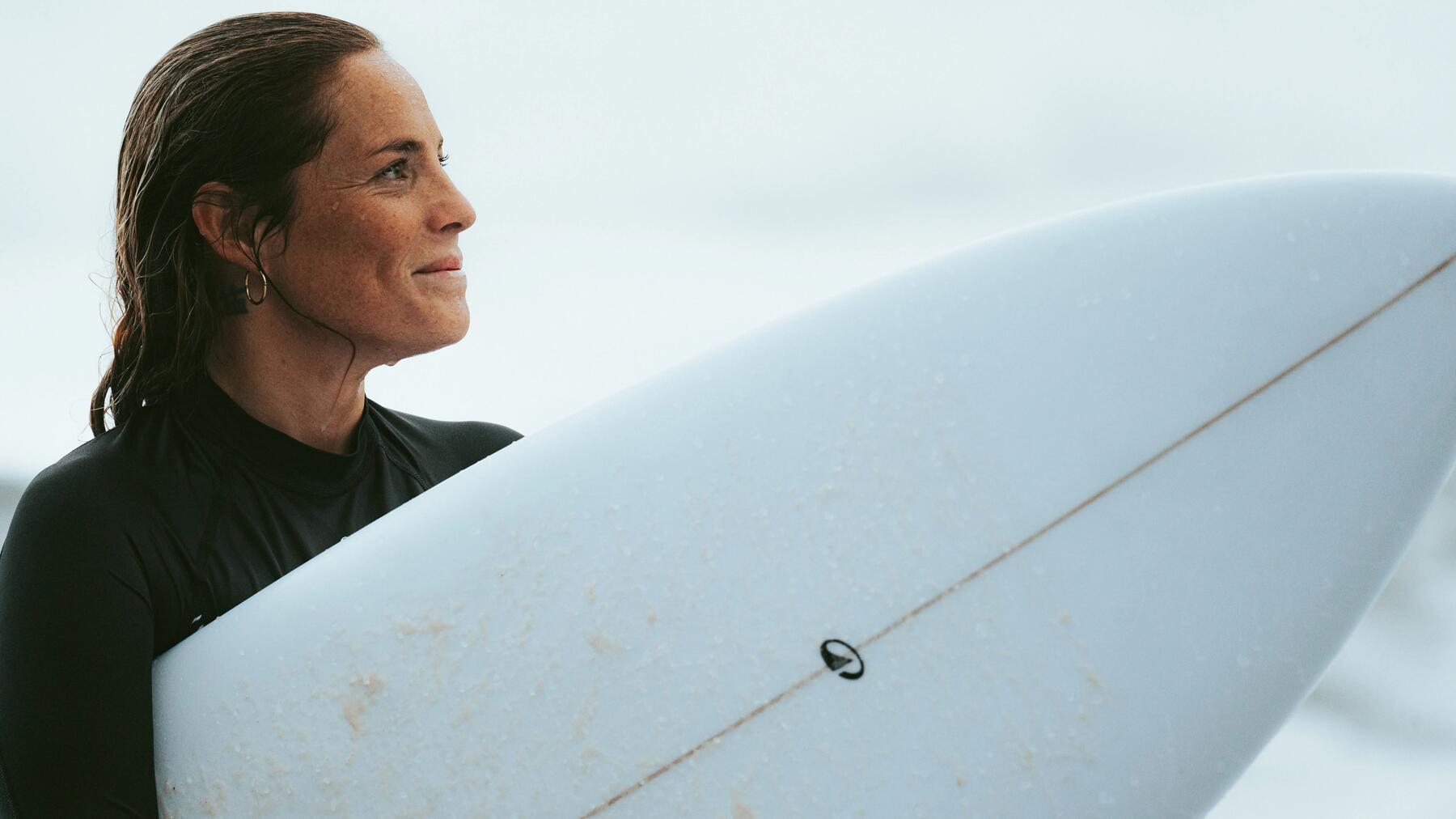 woman with here surf board under the arm walking on a beach