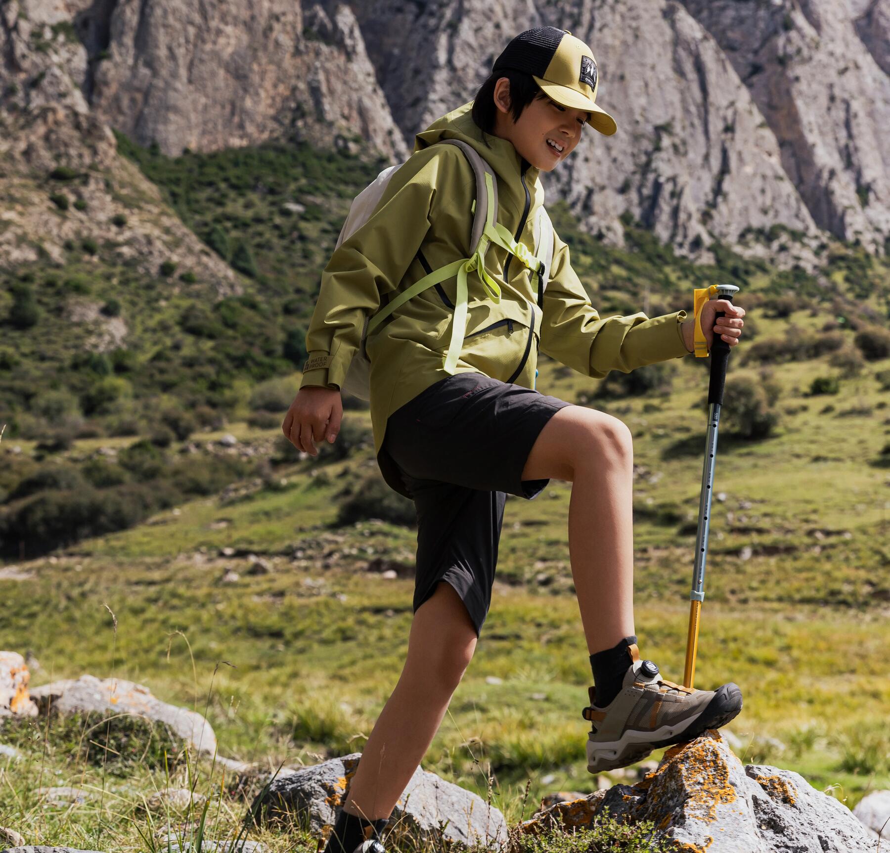 Ein Kind ist mit Wanderstöcken in den Bergen unterwegs