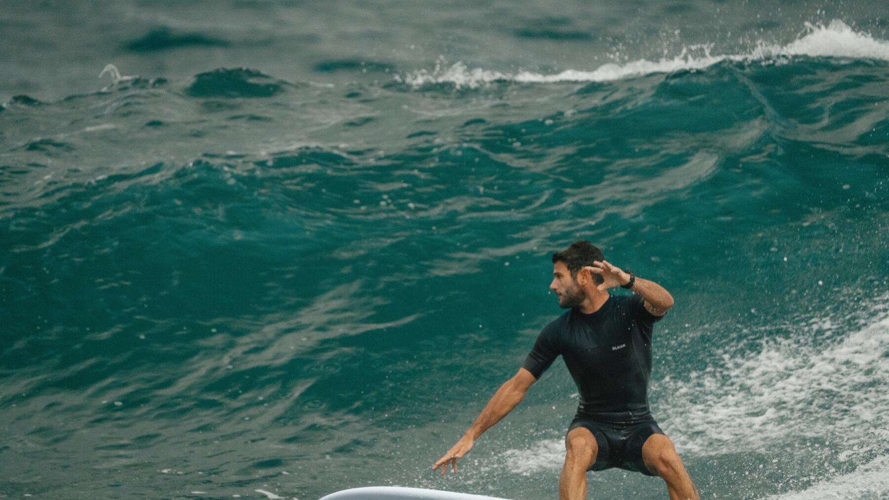 woman walking on a beach to reach the water with her surf board