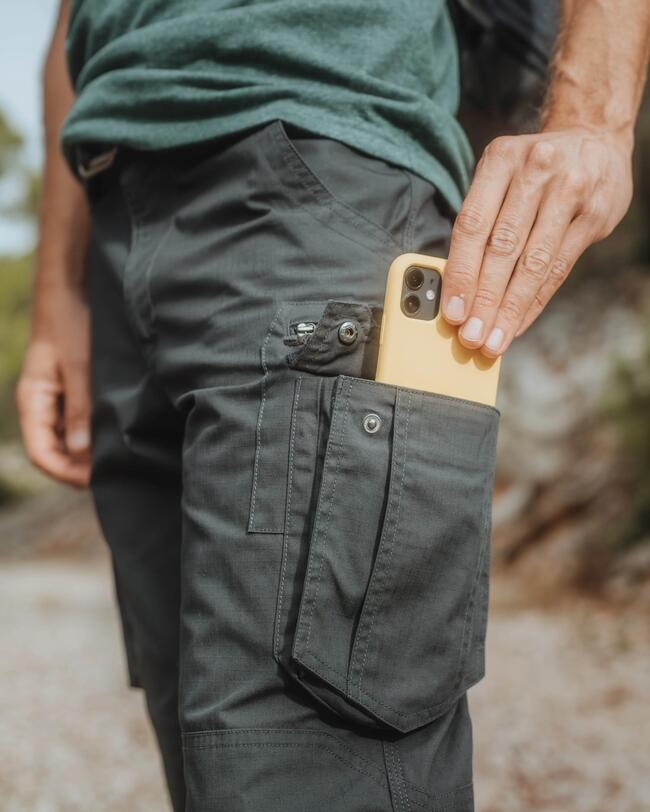 Person nimmt aus der Wanderhose mit Tasche ein Handy
