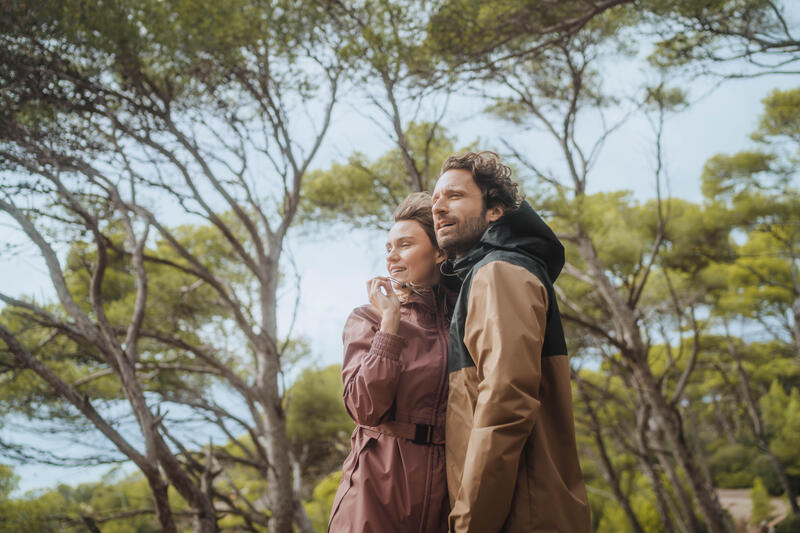 Par u prirodi, žena nosi dugu Quechua NH100 jaknu u boji ružičastog taupea dok uživaju u prolećnom povetarcu.