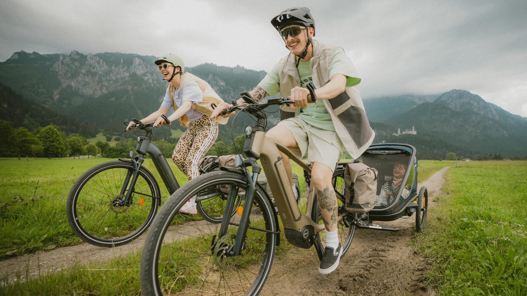 Kobieta i mężczyzna w kaskach rowerowych jadący elektrycznymi rowerami górskimi marki Rockrider
