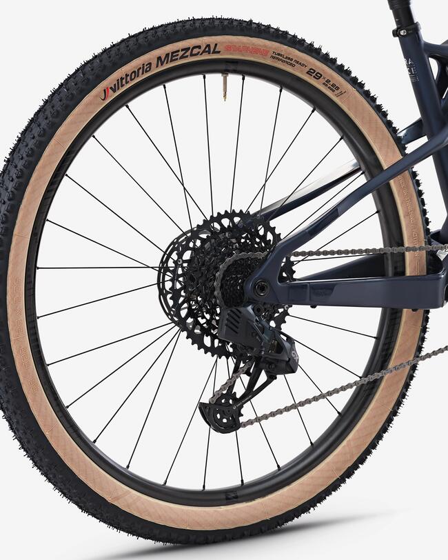 Großer Fahrradreifen mit sandfarbener Seitenwand, schwarzem Profil, dünnen Speichen und dunklem Rahmen in mattem Finish.