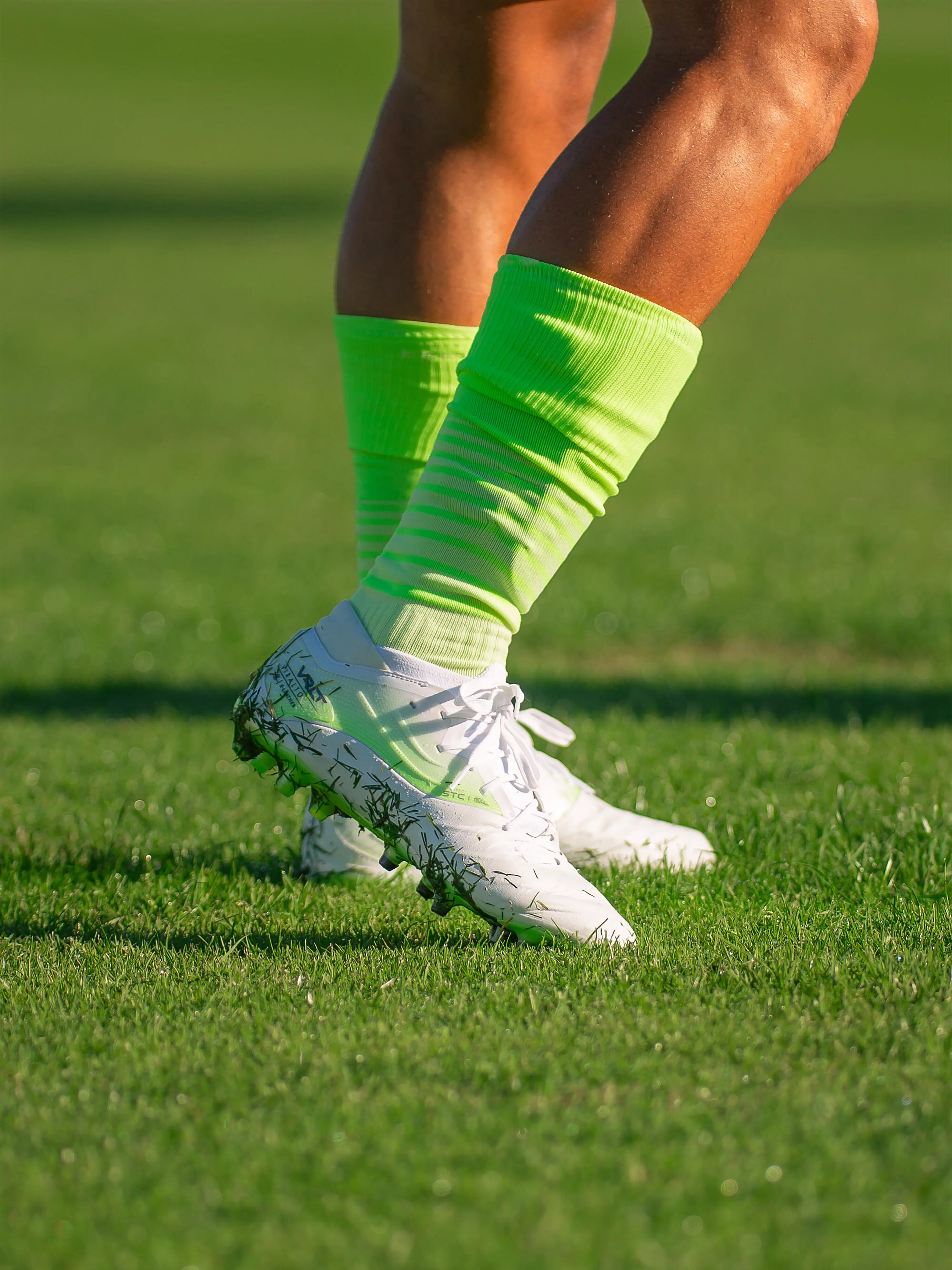 Kipsta Viralto IV Pro weiß/neon getragen auf einem Fußballplatz.