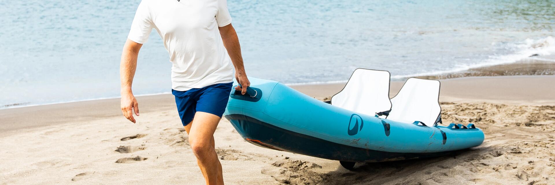 Mężczyzna idący z kajakiem po plaży