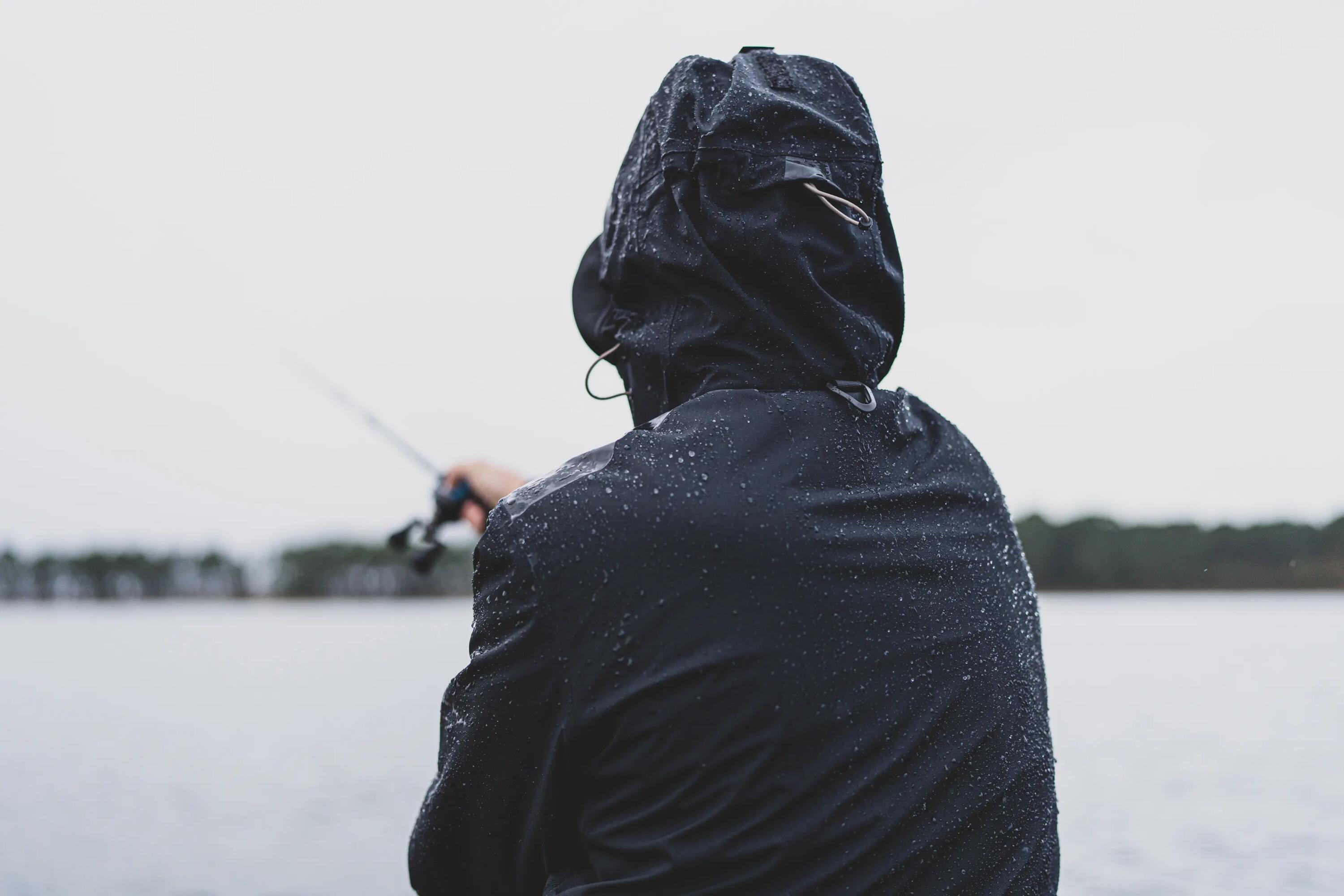 Ein Angler in Regenbekleidung wirft sein Köder aus