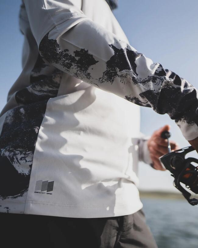 Angler mit UV-Shirt steht am Wasser und angelt