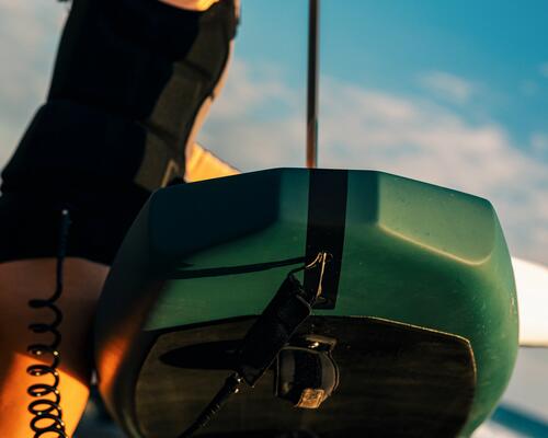 rideuse portant sa planche de wing foil au dessus de la tête