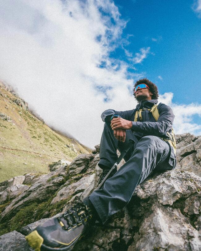 Mann sitzt auf Fels bei einer Wanderung