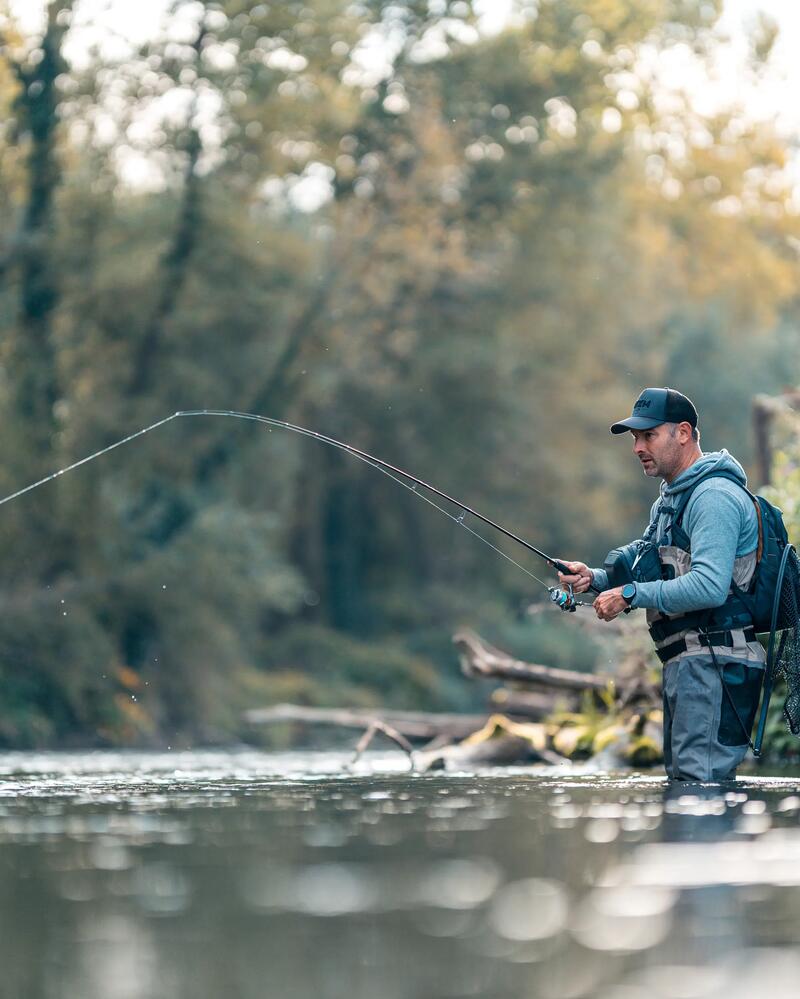 ANgler steht im Wasser und Angelt auf Forelle
