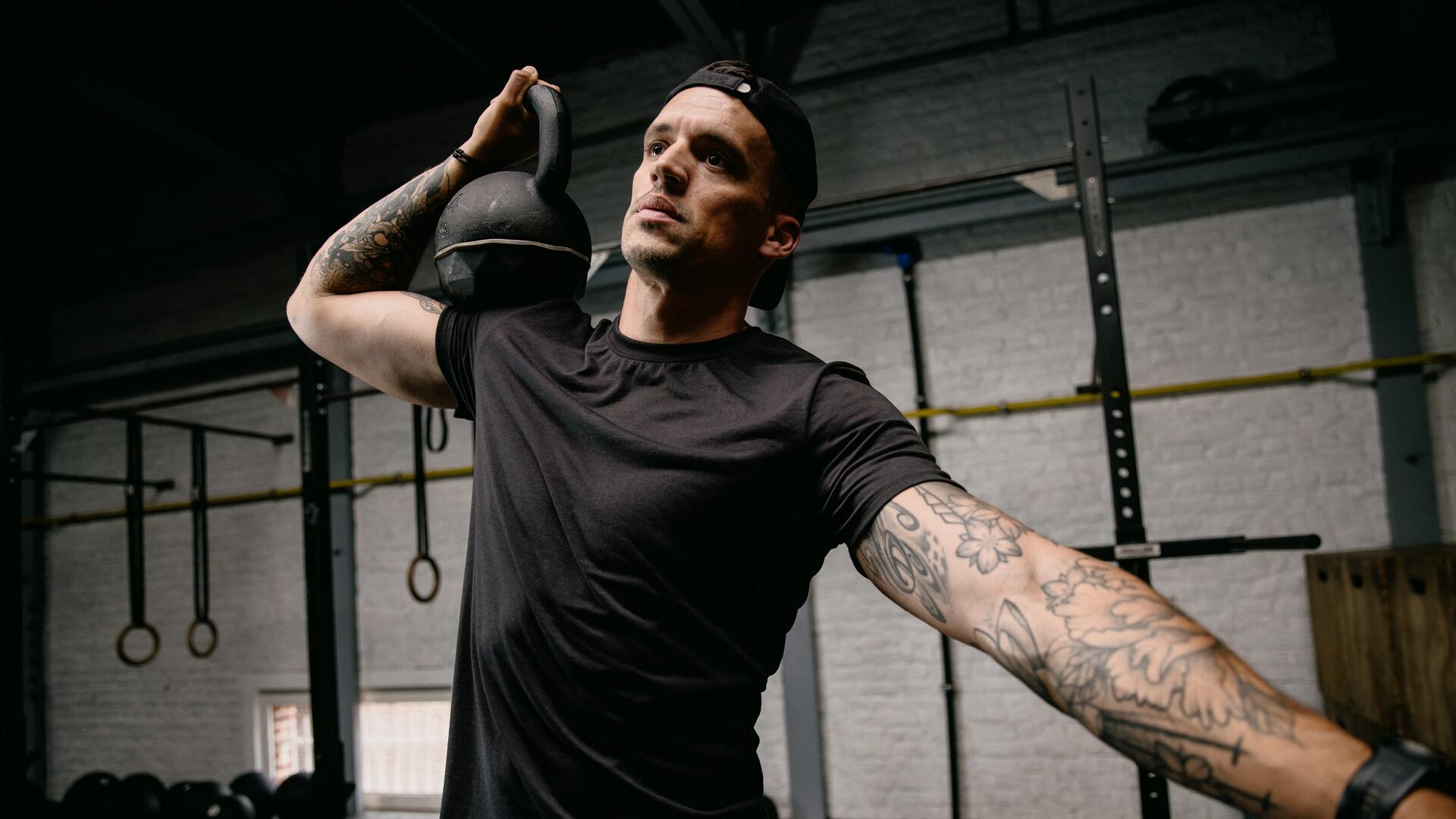 Mężczyzna trenujący crossfit trzymając kettlebell na ramieniu