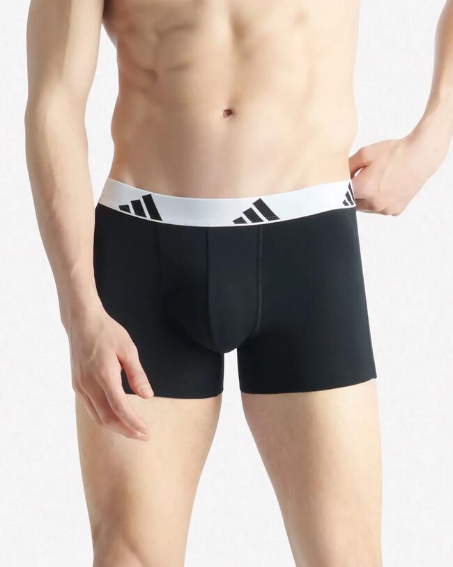 Männliches Model in schwarzen, eng anliegenden Boxershorts mit weißem Adidas-Logo-Bund.
