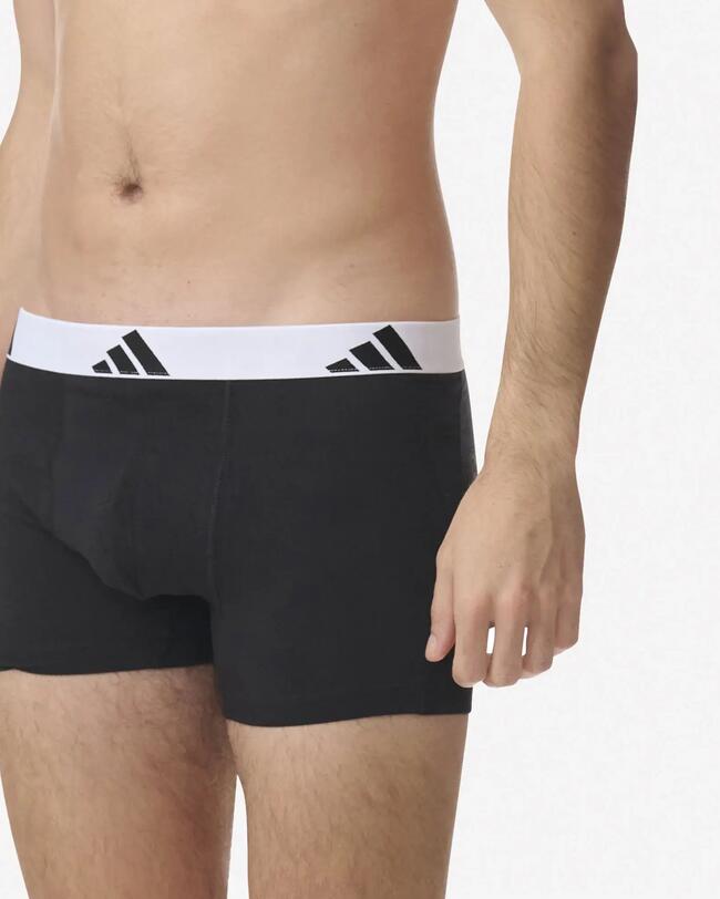 Seitenansicht eines Mannes in schwarzen, eng anliegenden Boxershorts mit Adidas-Logo-Bund.