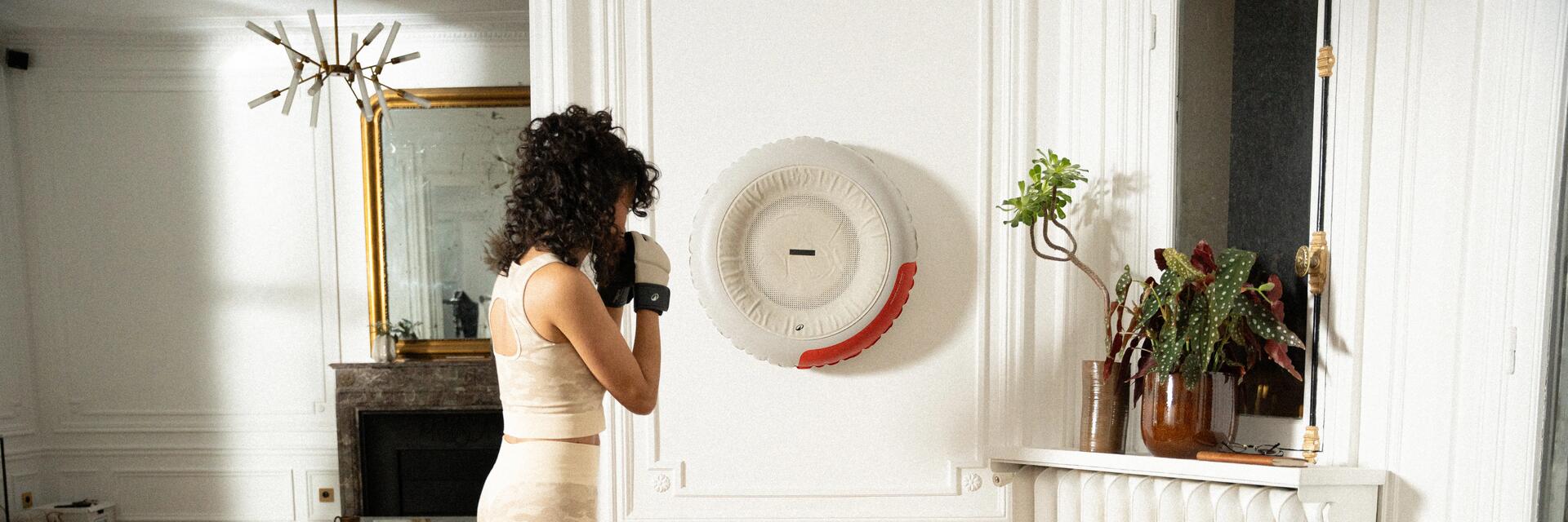Frau boxt gegen einen punching bag an der Wand