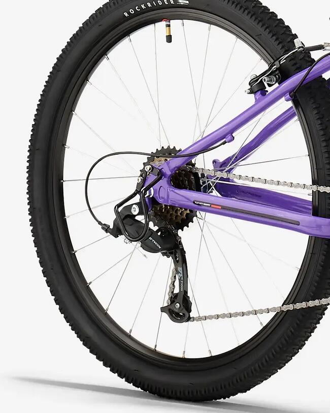 Lila Mountainbike mit schwarzem Lenker, griffigen Reifen und schmalem Sattel. Starkes, modernes Design auf weißem Hintergrund. Breite Reifen, Umwerfer, Kasette, Kette.