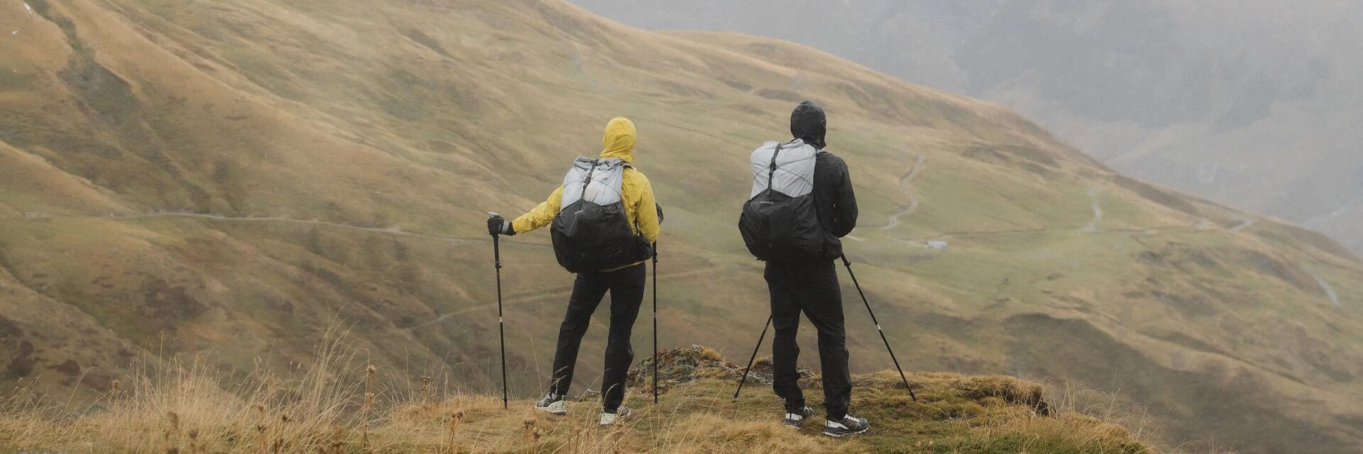 Ludzie z plecakami i z kijkami trekkingowymi wędrujący po górach