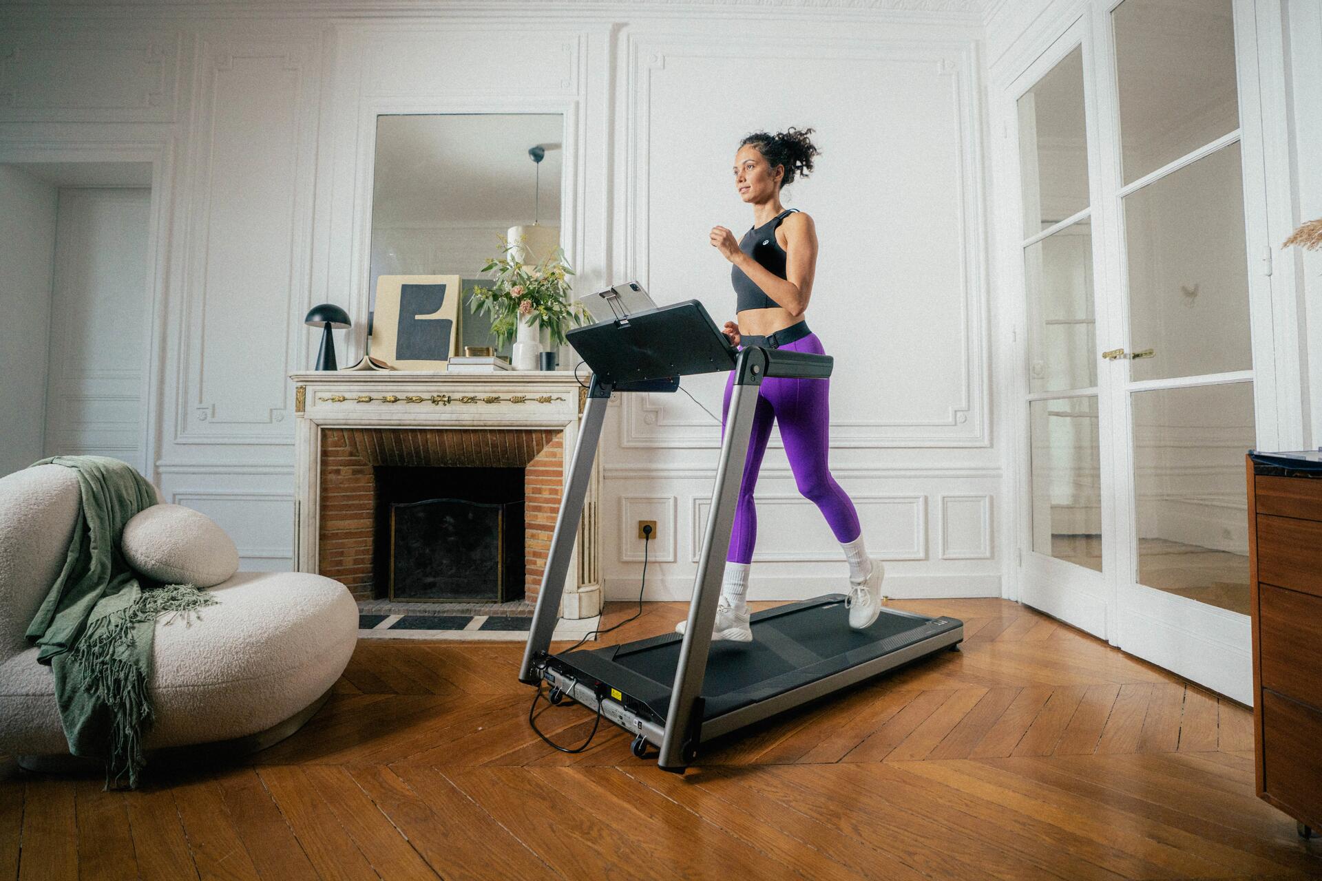 Kobieta w odzieży fitness biegnąca na bieżni domowej