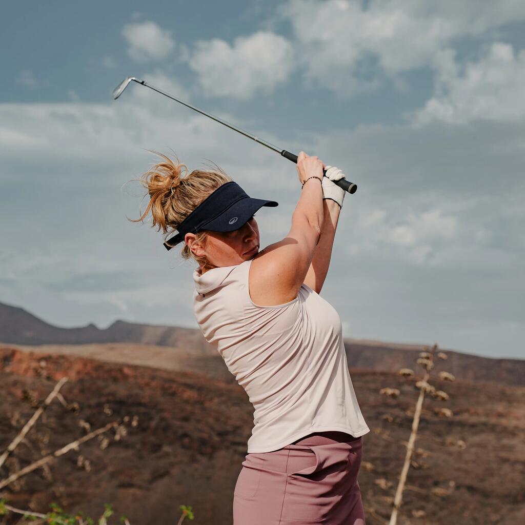 Eine Frau die auf einem Golfplatz einen Golfschläger schwingt.