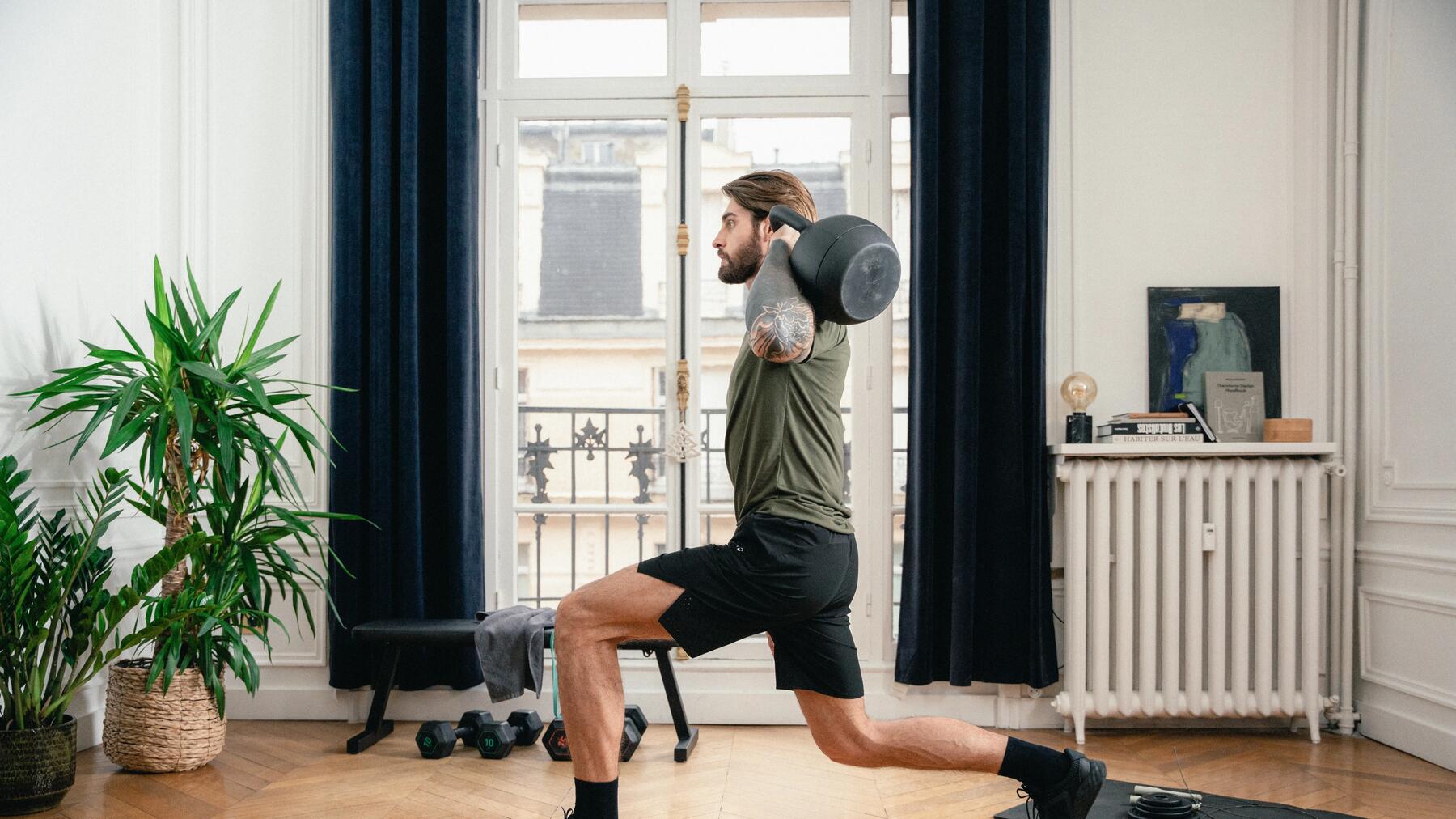 Mężczyzna ćwiczący zakroki z kettlebell przy uszach