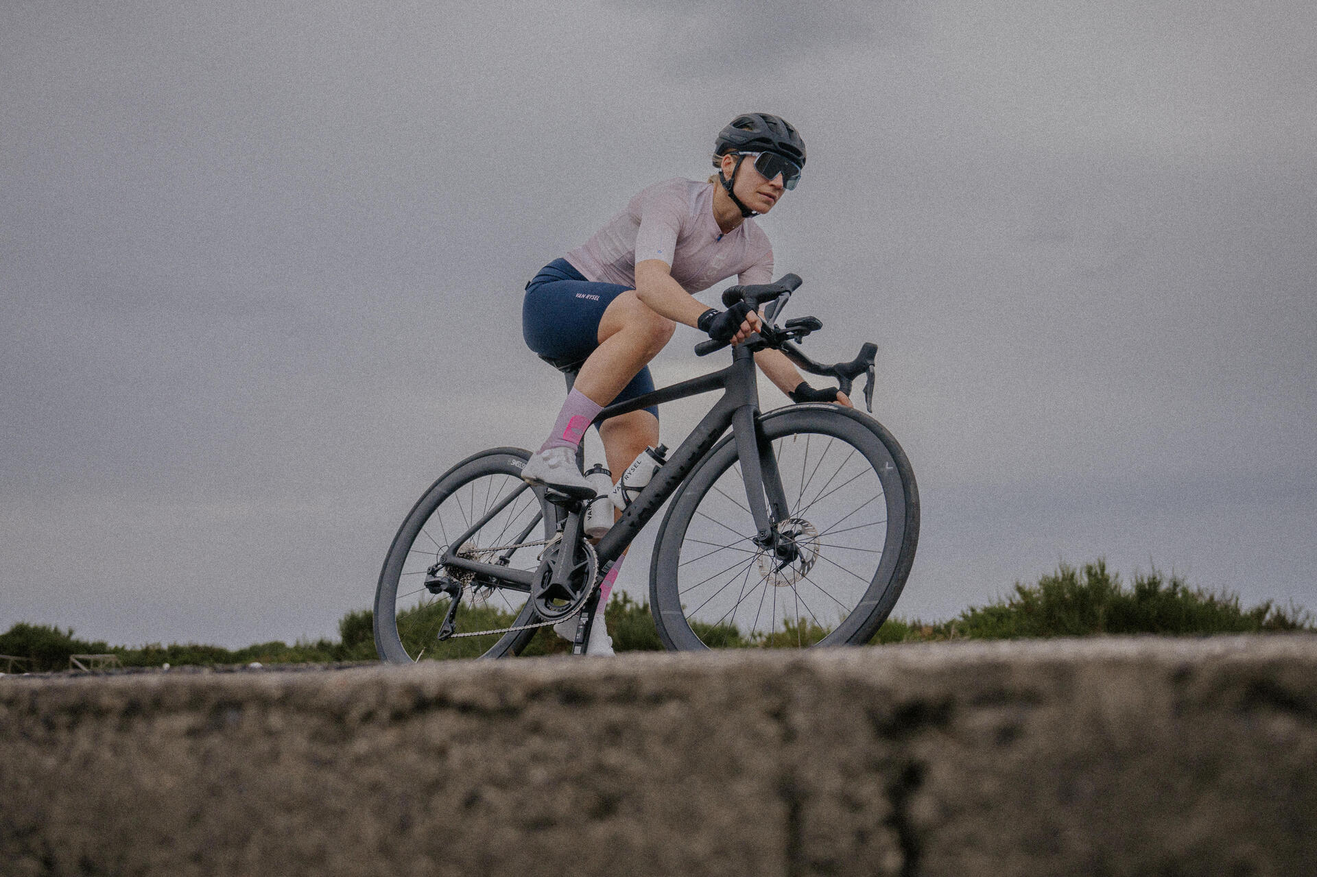 Kobieta w odzieży rowerowej w kasku i w okularach jadąca na rowerze