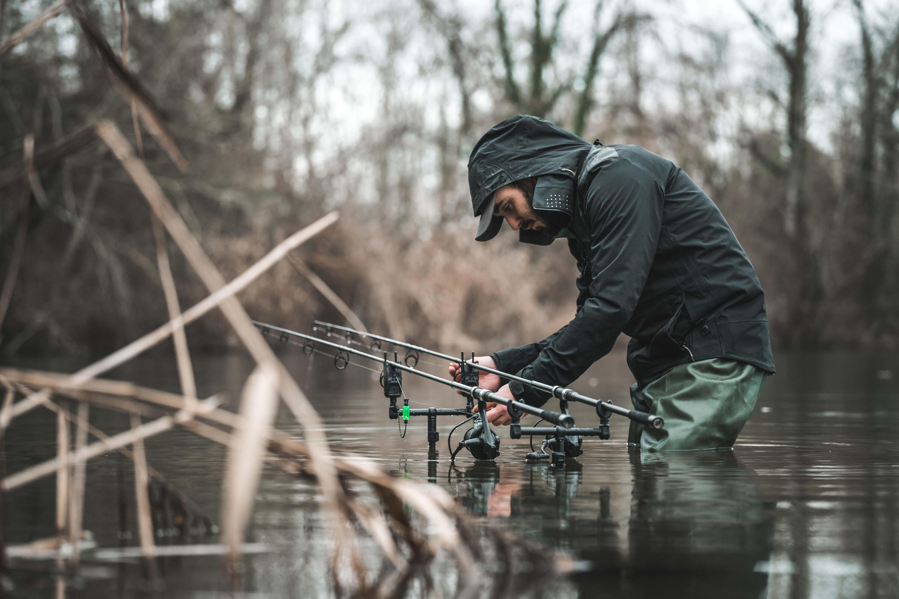 Ein Angler in Regenbekleidung wirft sein Köder aus