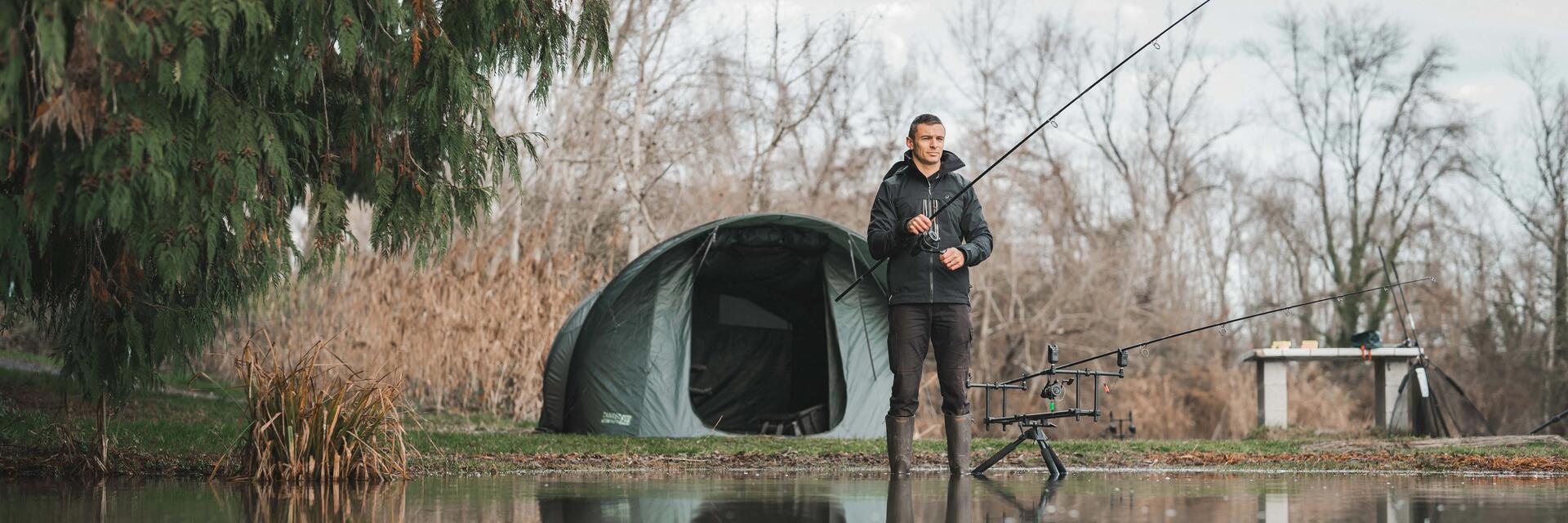 Ein Angler steht vor einem Angelzelt mit Rute in der Hand