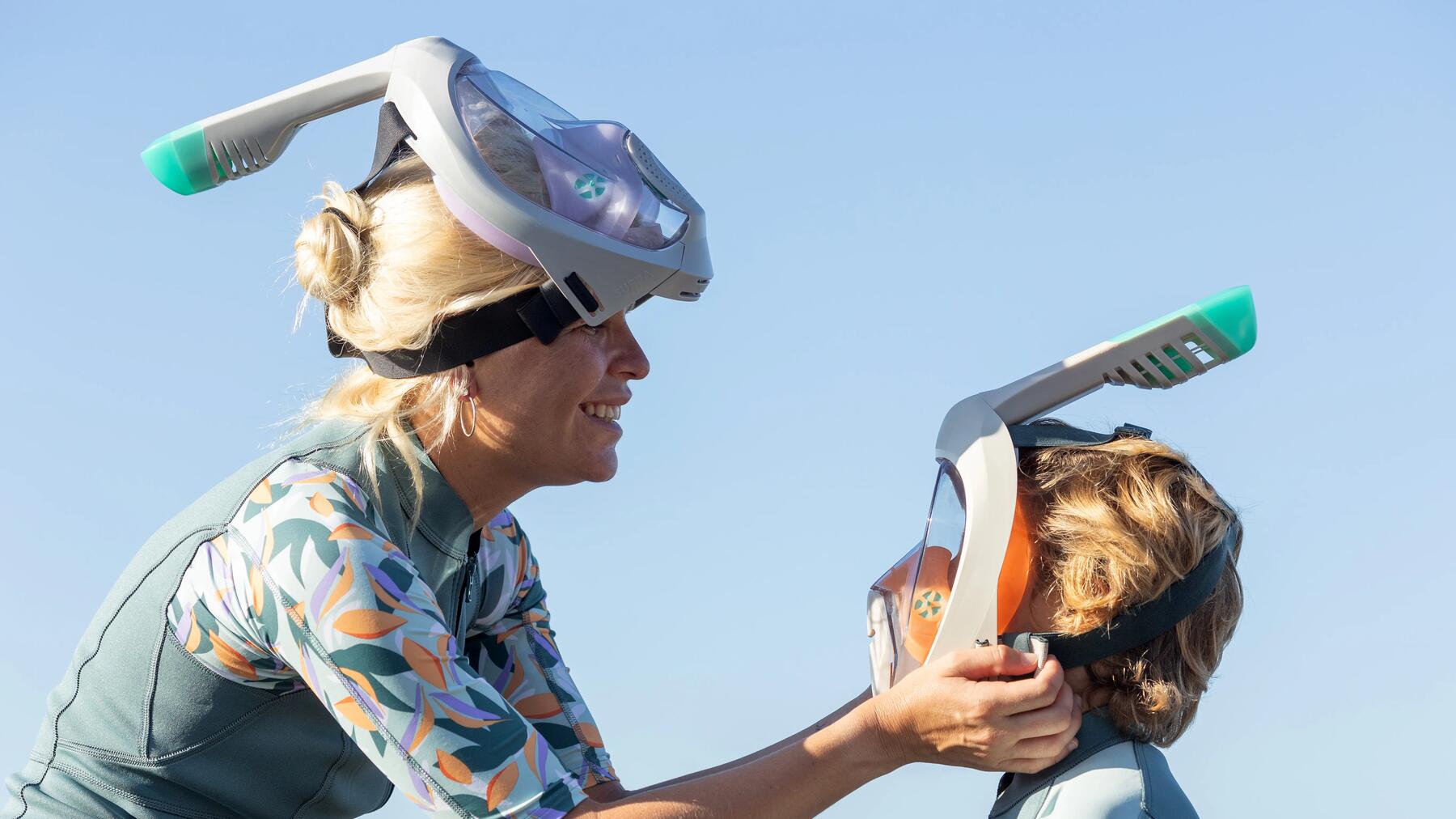 Frau zieht einem Kind eine Tauchmaske an