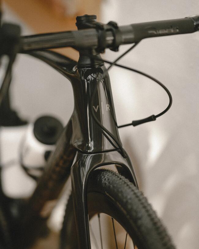 Schwarzes Fahrrad mit glänzendem Rahmen und geschwungenen Lenkergriffen, weiche Schatten auf weißer Wand.