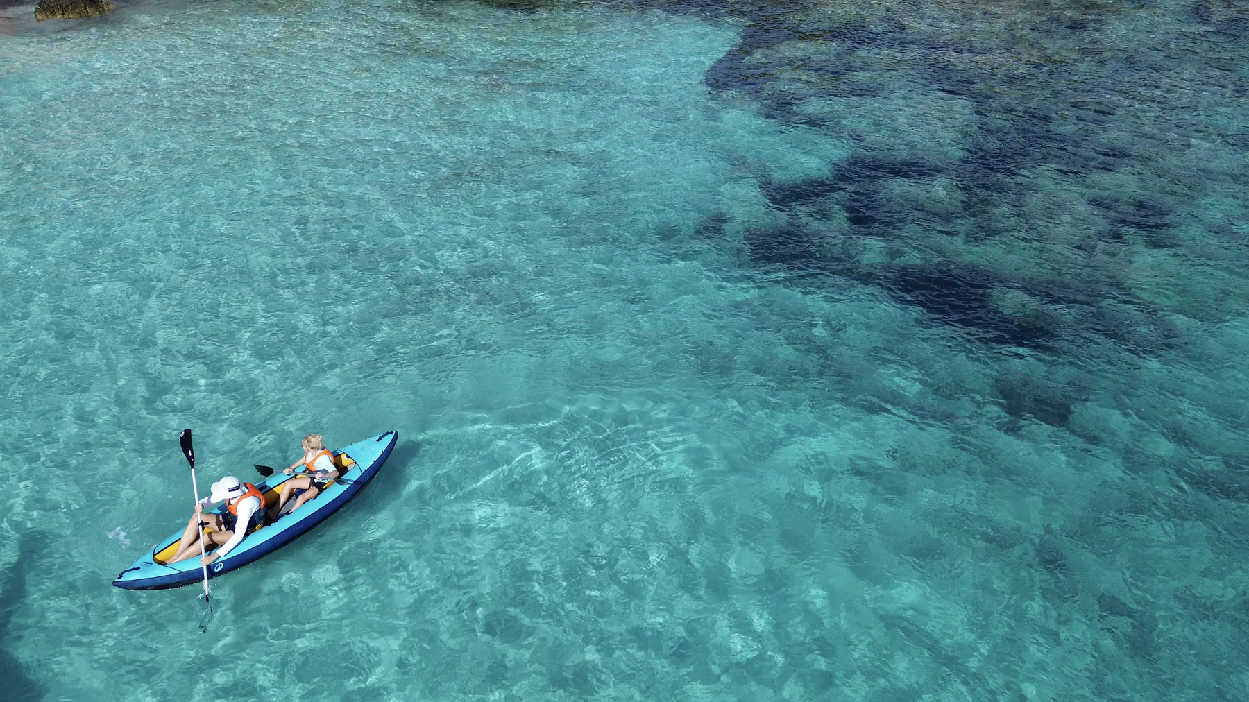 Zwei Personen fahren im kristallklaren Wasser Kajak