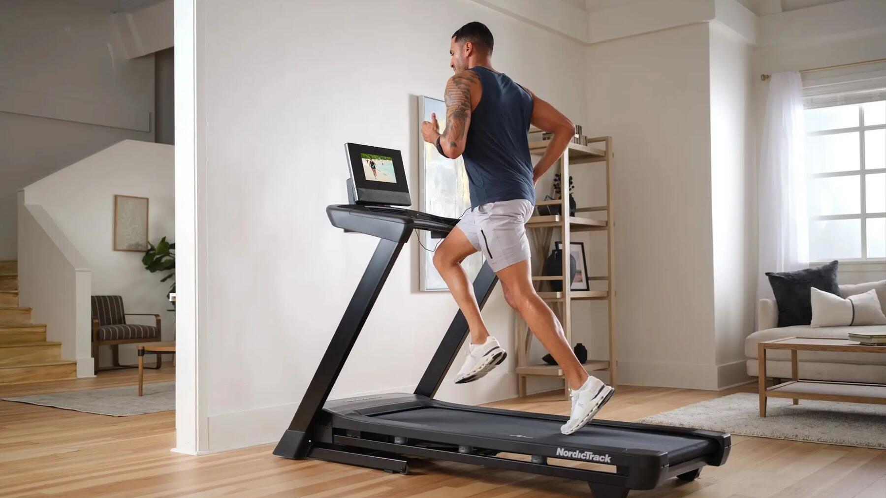Mann beim schnellen Gehen in seinem Wohnzimmer in Sportklamotten und passenden Joggingschuhen